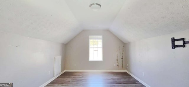 additional living space featuring lofted ceiling, dark hardwood / wood-style floors, and a textured ceiling