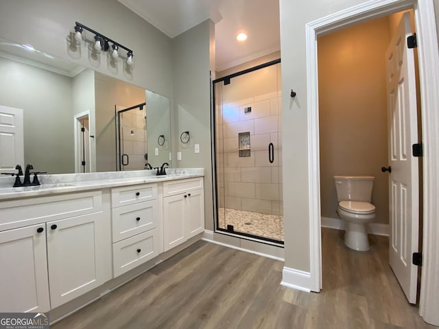 bathroom featuring hardwood / wood-style flooring, toilet, vanity, and a shower with door