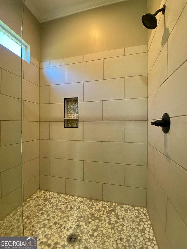 bathroom featuring crown molding and a tile shower