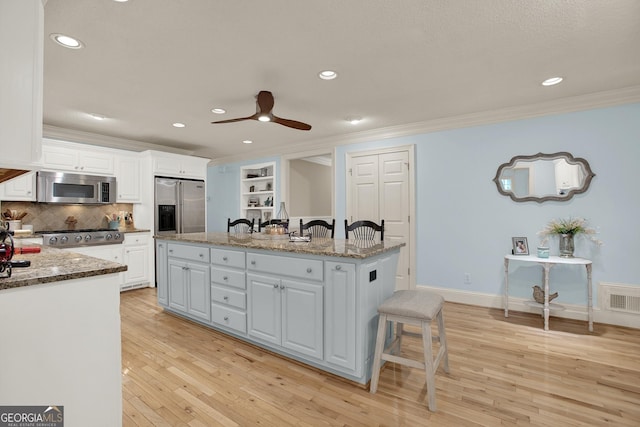 kitchen featuring dark stone countertops, stainless steel appliances, white cabinets, and a kitchen island