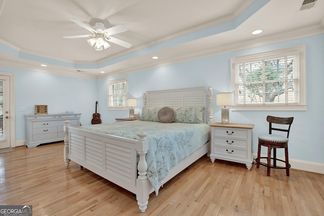 bedroom featuring a raised ceiling, ceiling fan, and light hardwood / wood-style flooring