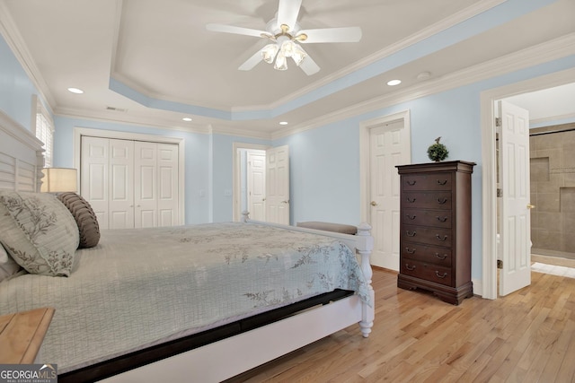 bedroom featuring connected bathroom, ornamental molding, ceiling fan, light hardwood / wood-style floors, and a raised ceiling