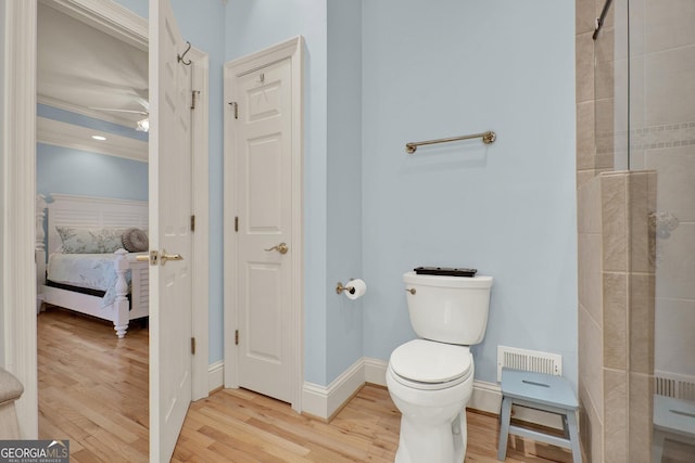 bathroom with hardwood / wood-style flooring, toilet, walk in shower, and crown molding