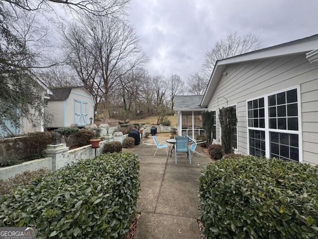 view of patio / terrace featuring a sunroom and a storage unit