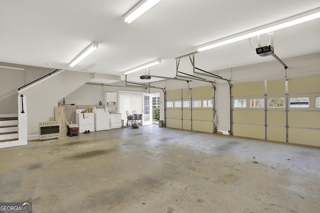 garage featuring a garage door opener, washing machine and dryer, and heating unit