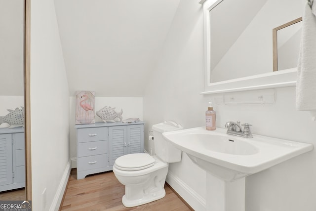 bathroom with lofted ceiling, hardwood / wood-style floors, sink, and toilet