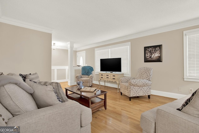 living room with hardwood / wood-style floors, crown molding, and ornate columns