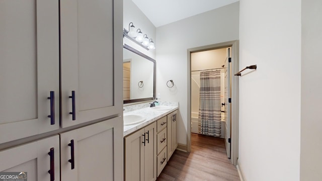 bathroom with hardwood / wood-style floors, vanity, and shower / tub combo