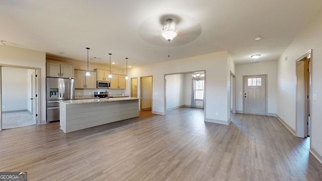 kitchen featuring decorative light fixtures, a center island with sink, stainless steel appliances, and light hardwood / wood-style flooring