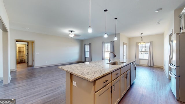 kitchen featuring an island with sink, stainless steel appliances, decorative light fixtures, dark wood-type flooring, and sink