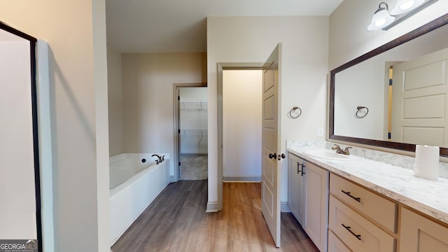 bathroom with hardwood / wood-style flooring, a tub, and vanity