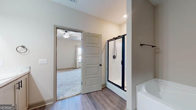 bathroom with independent shower and bath, hardwood / wood-style flooring, and vanity