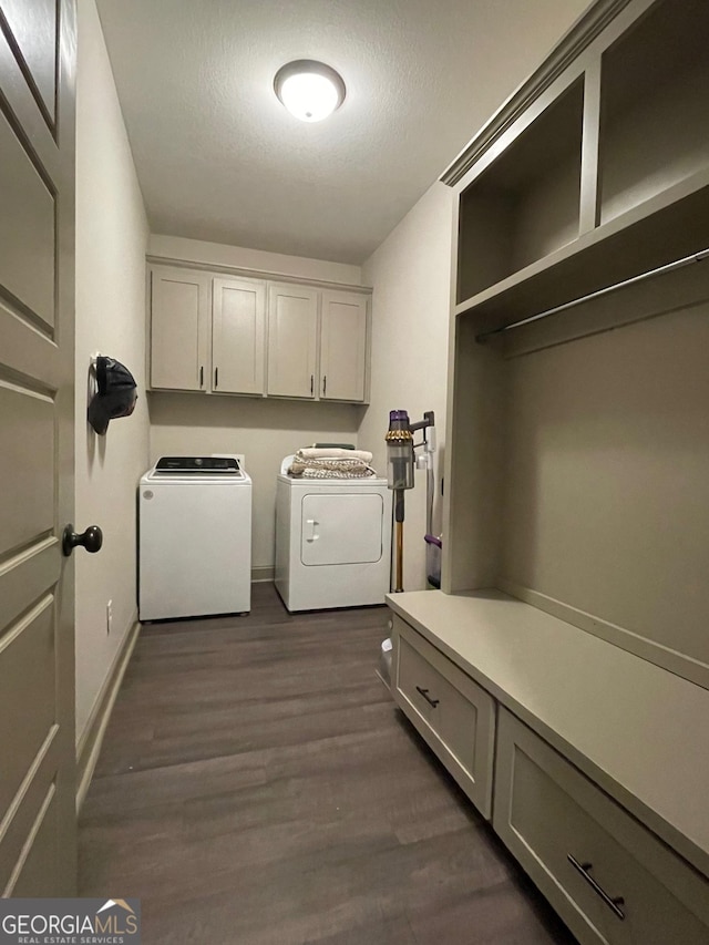 laundry room featuring dark wood-type flooring, separate washer and dryer, a textured ceiling, and cabinets