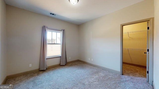 unfurnished bedroom with a spacious closet, a closet, and light carpet