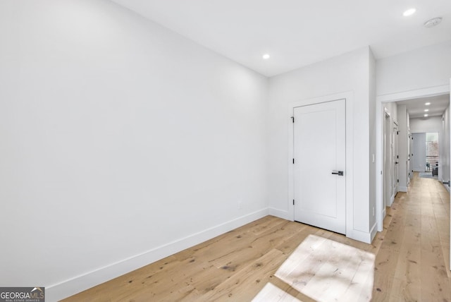 hall featuring baseboards, recessed lighting, and light wood-style floors