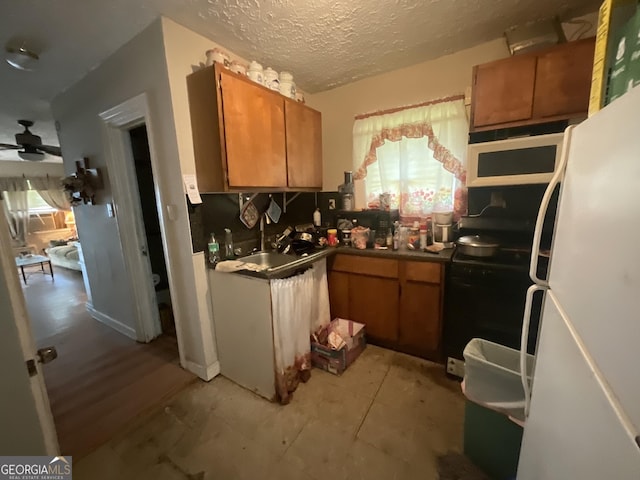 kitchen with a textured ceiling, white refrigerator, sink, range with electric cooktop, and ceiling fan