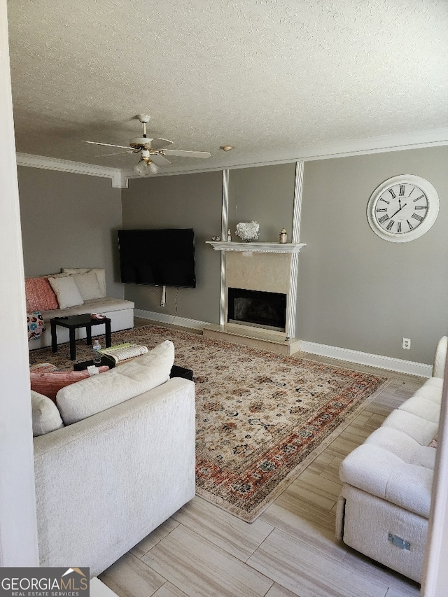 living room featuring ceiling fan, a textured ceiling, and ornamental molding