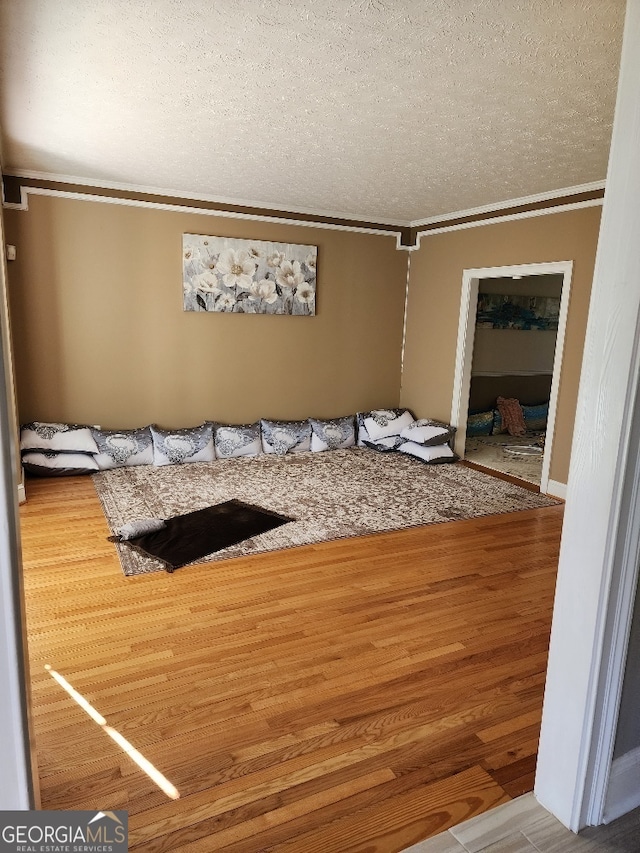 interior space with a textured ceiling, crown molding, and hardwood / wood-style floors