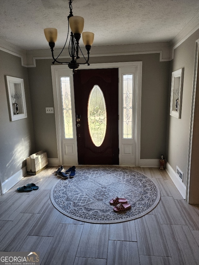 entryway featuring plenty of natural light, a textured ceiling, and an inviting chandelier