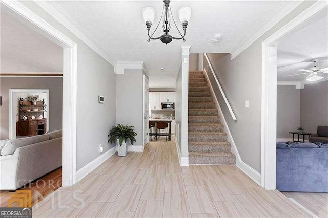 entrance foyer with a textured ceiling, crown molding, and ceiling fan with notable chandelier