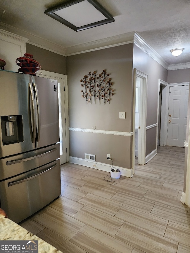 kitchen with a textured ceiling, stainless steel fridge with ice dispenser, and crown molding