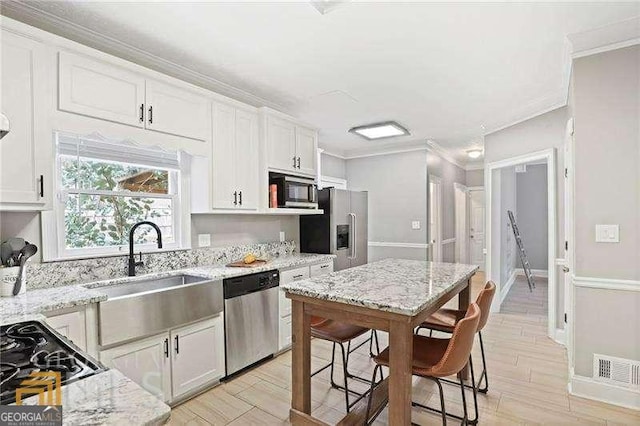 kitchen with sink, crown molding, stainless steel appliances, white cabinets, and light stone counters