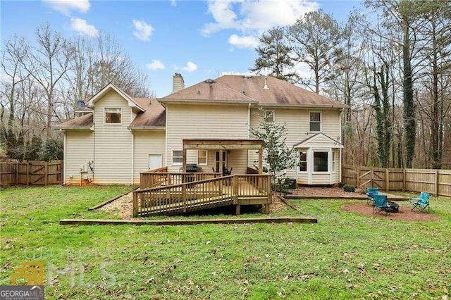 rear view of house with a deck, an outdoor fire pit, and a yard