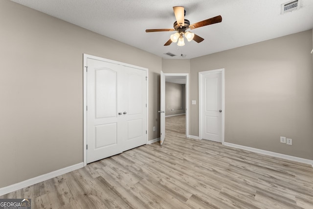 unfurnished bedroom featuring ceiling fan, light wood-type flooring, and a textured ceiling