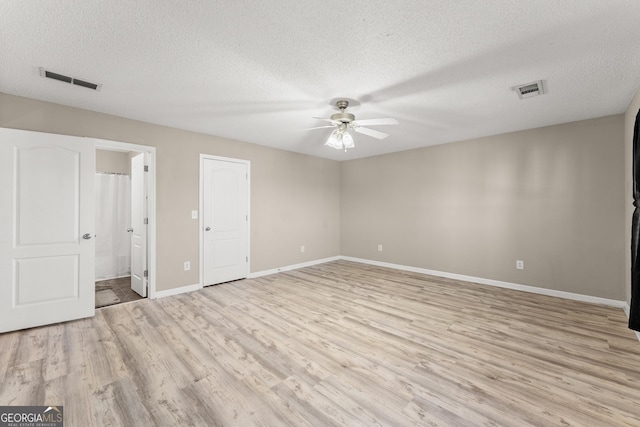 unfurnished bedroom with ceiling fan, ensuite bath, a textured ceiling, and light hardwood / wood-style floors