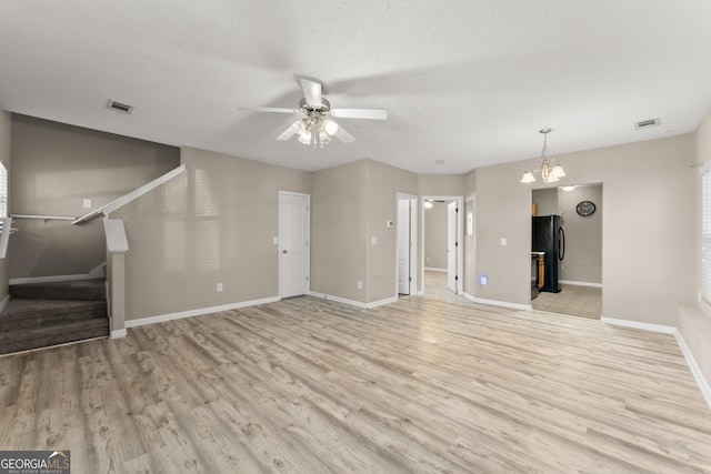 unfurnished living room featuring light wood-type flooring, a textured ceiling, and ceiling fan with notable chandelier