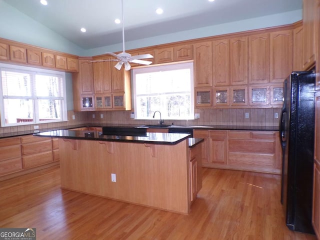 kitchen with black refrigerator, light hardwood / wood-style floors, a breakfast bar area, and a center island