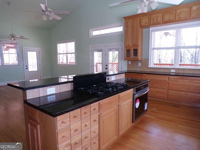 kitchen with light hardwood / wood-style floors, stainless steel oven, backsplash, black gas stovetop, and a center island