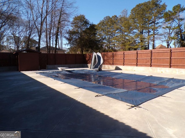 view of swimming pool with a patio area, a water slide, and a diving board