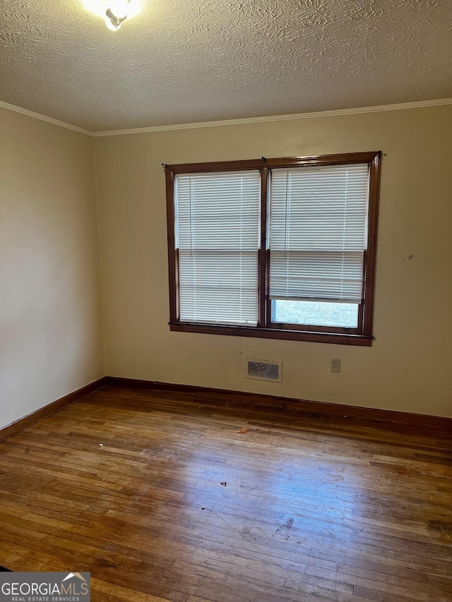 unfurnished room featuring a textured ceiling, dark hardwood / wood-style flooring, and ornamental molding