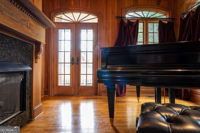 misc room featuring a premium fireplace, wood walls, and french doors