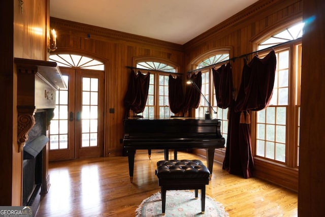 misc room with french doors, wood walls, ornamental molding, and light hardwood / wood-style flooring