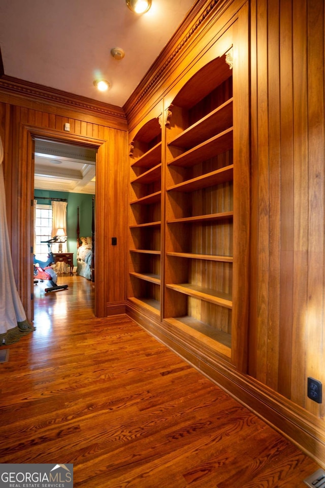 corridor with wooden walls, ornamental molding, and hardwood / wood-style floors