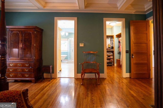 sitting room with beam ceiling, wood-type flooring, coffered ceiling, and ornamental molding