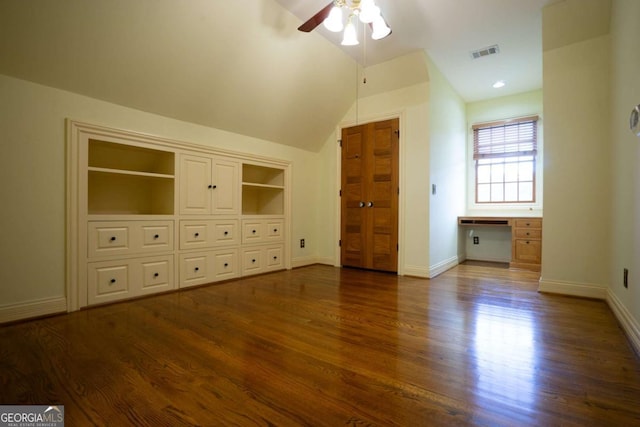 interior space featuring ceiling fan, lofted ceiling, dark hardwood / wood-style floors, built in desk, and built in shelves