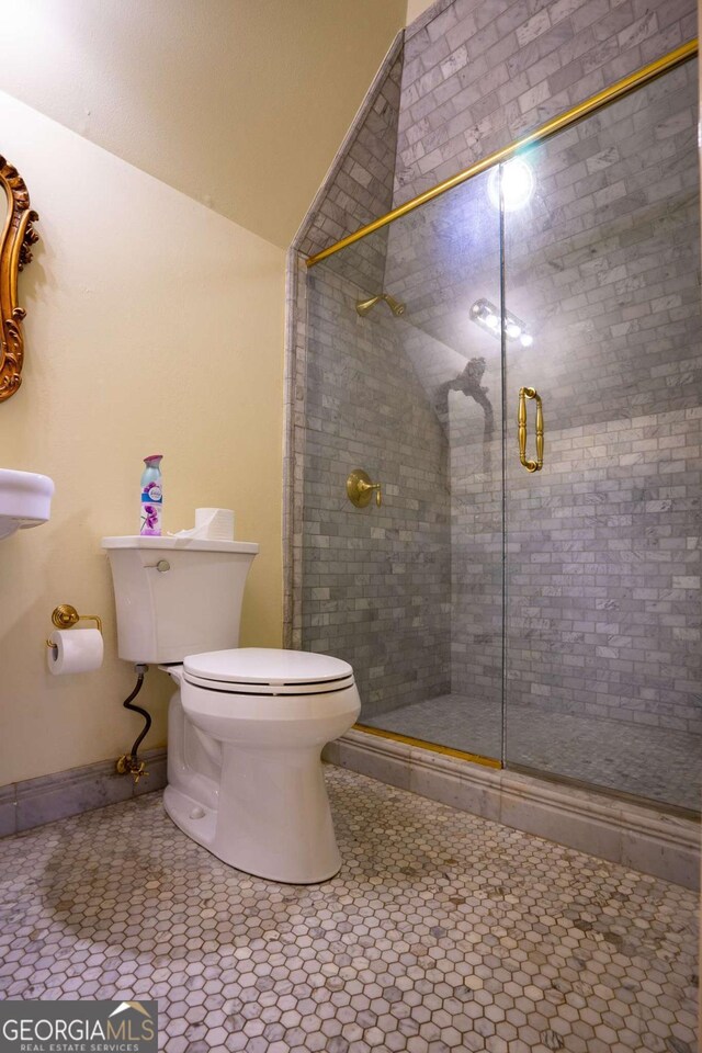 bathroom with toilet, tile patterned flooring, lofted ceiling, and a shower with shower door