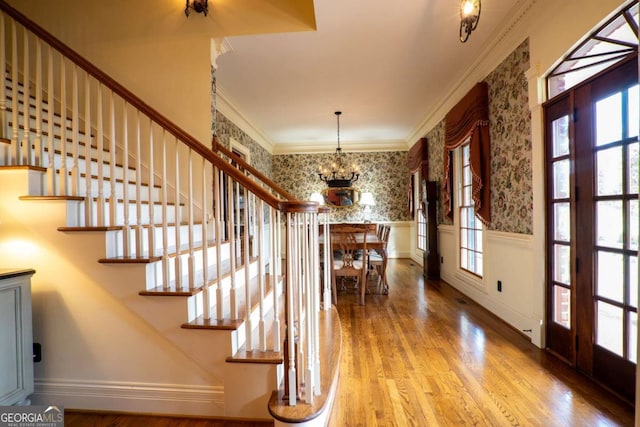 entryway with an inviting chandelier, crown molding, and wood-type flooring