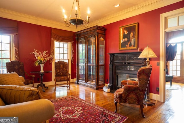 sitting room with a wealth of natural light, wood-type flooring, and a notable chandelier