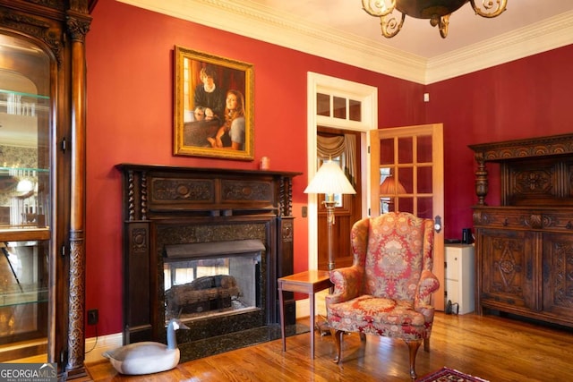 sitting room featuring a fireplace, ornamental molding, and hardwood / wood-style flooring