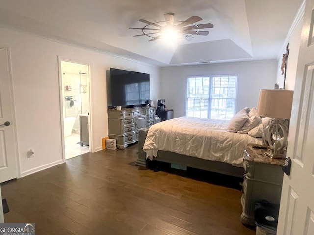 bedroom with a raised ceiling, ceiling fan, dark hardwood / wood-style flooring, and connected bathroom