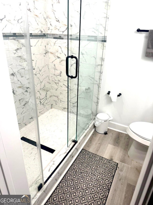 bathroom with a shower with shower door, toilet, and hardwood / wood-style floors