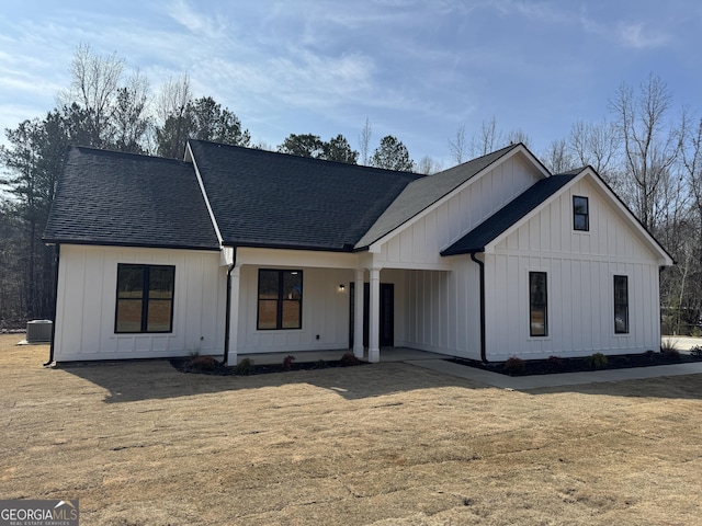 modern farmhouse style home with a front yard and central air condition unit