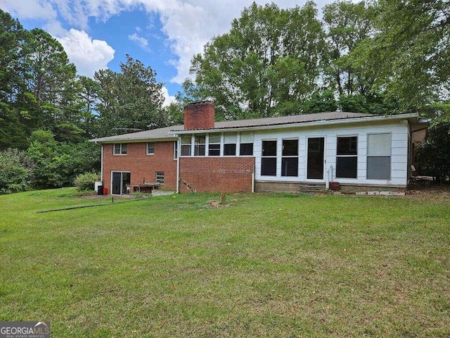 rear view of property featuring a lawn