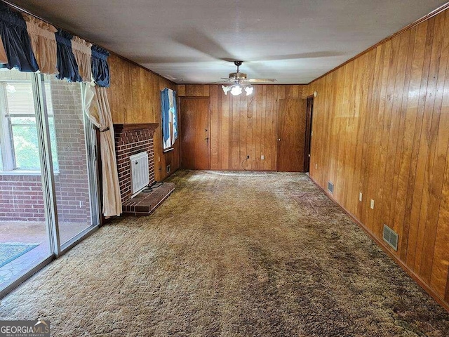 unfurnished living room with carpet, a healthy amount of sunlight, and wooden walls