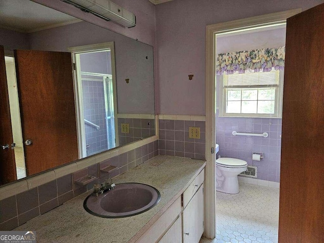 bathroom featuring toilet, crown molding, vanity, and tile walls