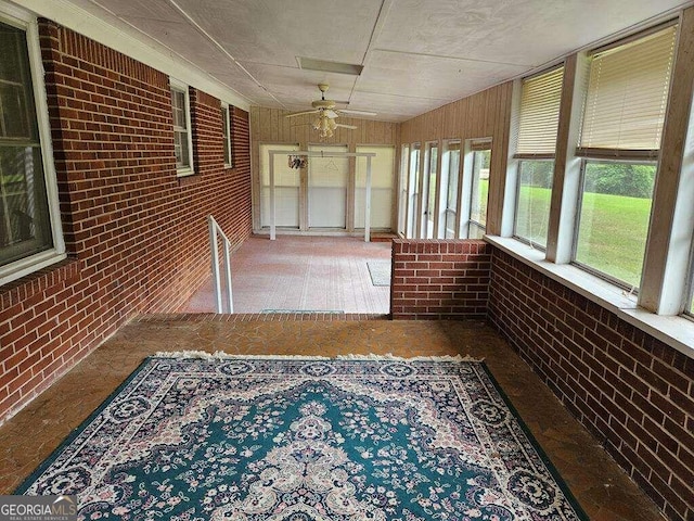 unfurnished sunroom with ceiling fan